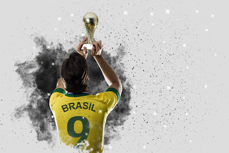 Brazilian soccer player coming out of a blast of smoke. celebrating with a trophy in his hand.の写真素材