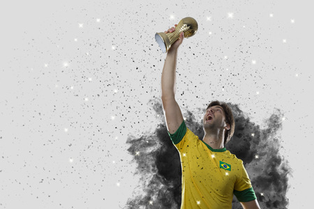 Brazilian soccer player coming out of a blast of smoke. celebrating with a trophy in his hand.の写真素材