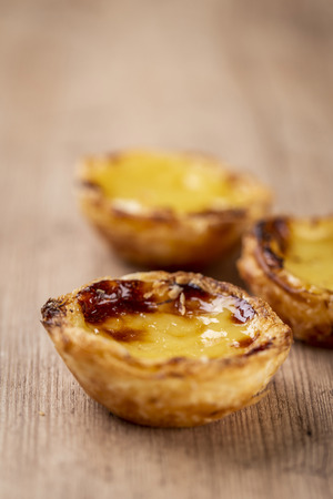Typical Portuguese custard pies - "Pastel de Nata" or "Pastel de Belem". traditional portuguese pastry. On a wooden table.の写真素材