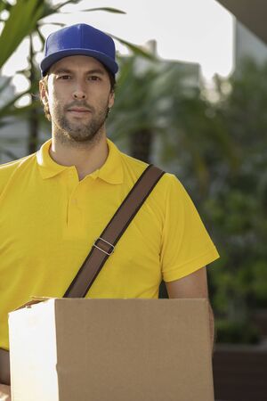 Brazilian mailman delivering a package on the street. Internet purchase being delivered at home.の写真素材