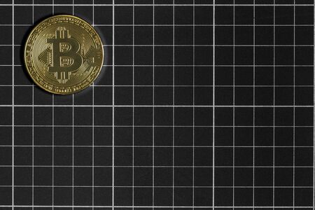 Physical bitcoin on top of a black and white grid board.の写真素材