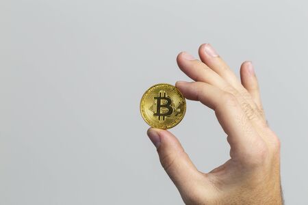 man hand holding a physical bitcoin in front of a white backgroundの写真素材