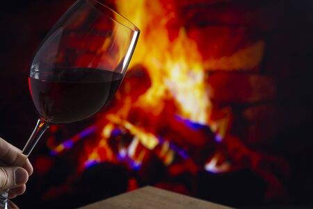 Glass of Wine on a wooden table in front of a fireplaceの写真素材
