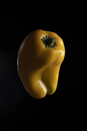 Yellow bell peppers lit on black backgroundの写真素材