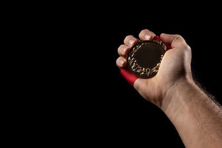 hand holding a gold medal on black with blank face for text, concept for winning or successの写真素材
