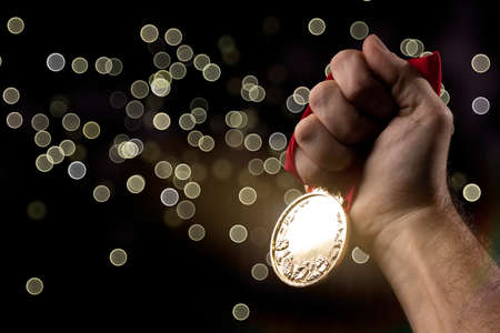 hand holding a gold medal on black with blank face for text, concept for winning or success