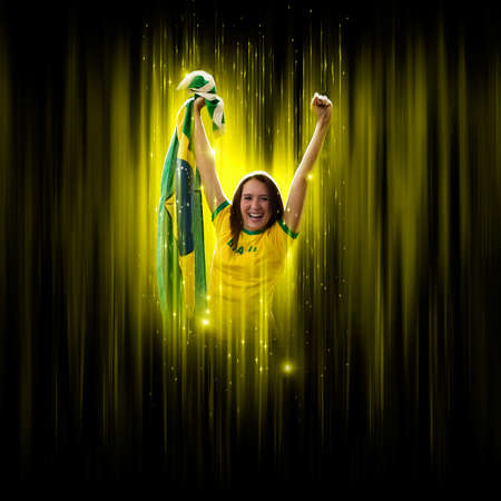 Brazilian woman fan, celebrating on a yellow and black backgroun, cheering for Brazil to be the champion.の写真素材