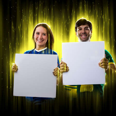 Brazilian couple holding white empty boards on a black background, cheering for Brazil to be the champion.の写真素材