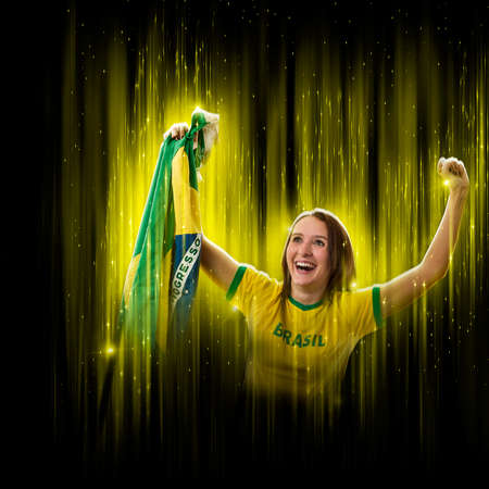 Brazilian woman fan, celebrating on a yellow and black backgroun, cheering for Brazil to be the champion.の写真素材