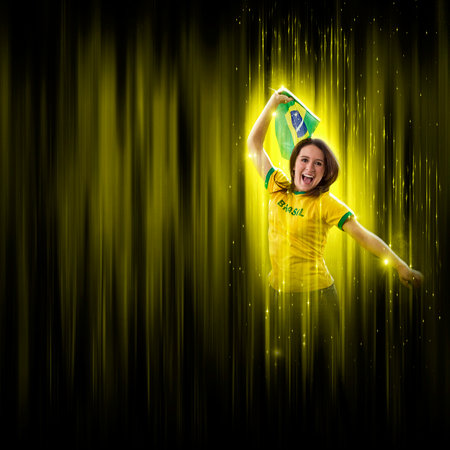 Brazilian woman fan, celebrating on a yellow and black backgroun, cheering for Brazil to be the champion.の写真素材