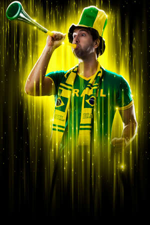 Brazilian fan, celebrating on a yellow and black backgroun, cheering for Brazil to be the champion.の写真素材