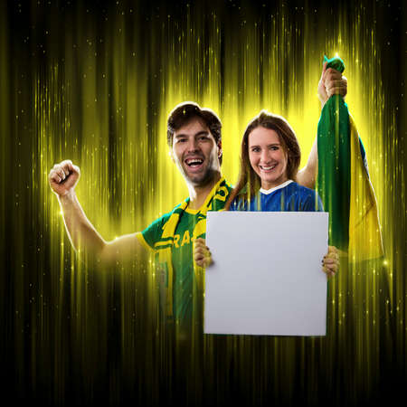 Brazilian couple holding white empty boards on a black background, cheering for Brazil to be the champion.の写真素材