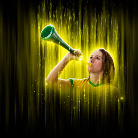 Brazilian woman fan, celebrating on a yellow and black backgroun, cheering for Brazil to be the champion.の写真素材