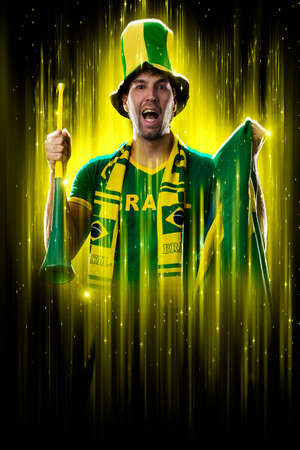 Brazilian fan, celebrating on a yellow and black backgroun, cheering for Brazil to be the champion.の写真素材