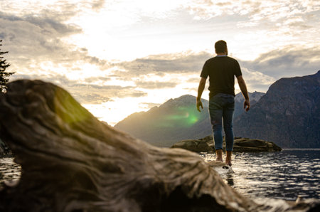 Man walking on the shore of a lake. Man looking at the sunsetの写真素材
