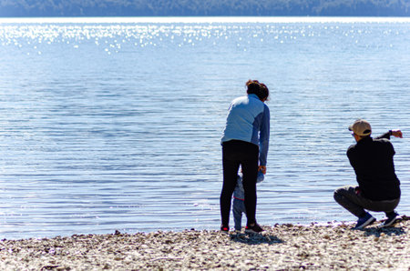 Mother and son sitting on the shore of a lake, back view