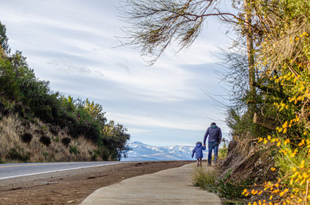 Father and son walking on the road to the top of the hillの写真素材