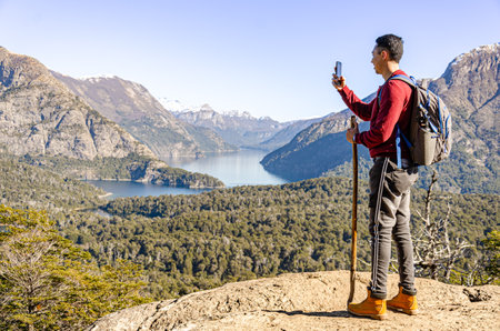 Hiker taking a picture of the landscape on top of Cerro Llao Llao, Bariloche, Patagonia Argentina.の写真素材