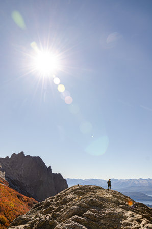 Hiker on top of a mountain with sun in the background.の写真素材