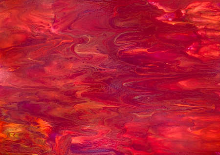 Photograph of fluid acrylic artwork.  The use of red, orange and yellow paint gives the impression of a sunset or fire.の写真素材