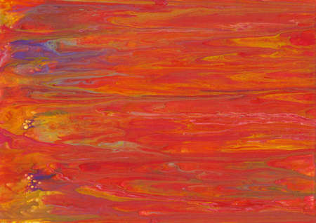 Photograph of fluid acrylic artwork.  The use of red, orange and yellow paint gives the impression of a sunset or fire.の写真素材