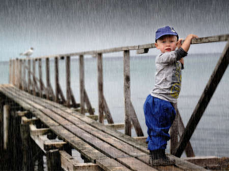 Waiting child by the sea in heavy storm                            の写真素材