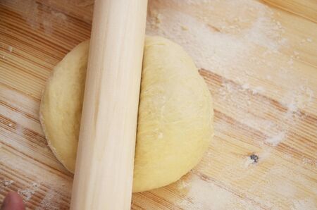 The rolling pin lies on the raw dough, for rolling on a wooden table. The process of preparing the...