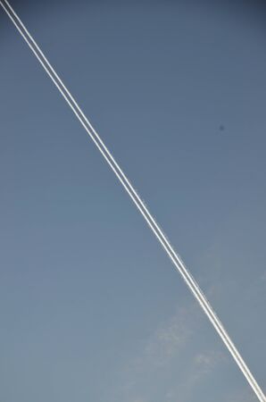 A diagonal line of smoke against the blue sky. A trace of an airplane in a cloudless sky. A double, clear line of smoke.の写真素材
