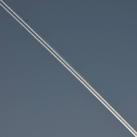 A white line of smoke diagonally across the dark blue sky. A trace of an airplane in a cloudless sky. A double, clear line of smoke in a clear sky.の写真素材