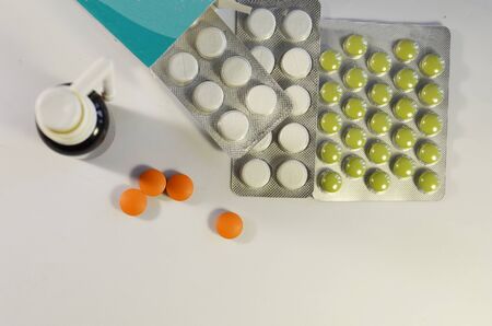 Medicines stand on a white background, at close range. Green pills in a package, colored pills and...