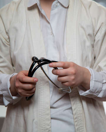A young female doctor holds a stethoscope. A medical worker in white medical clothing with a stethoscope. Close-up. Without a face.の写真素材