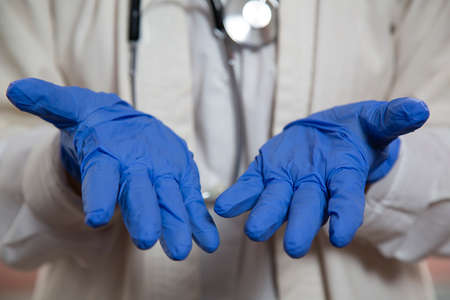 Doctor's hands in blue medical gloves. The palms of a female doctor in disposable gloves against the background of a stethoscope.の写真素材