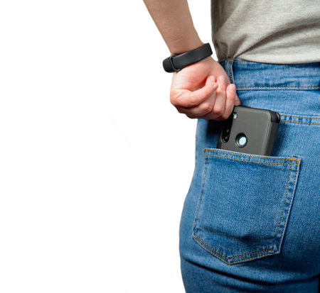 A mobile phone in the pocket of a girl in jeans. Isolated. At close range. The girl's hand pulls the...