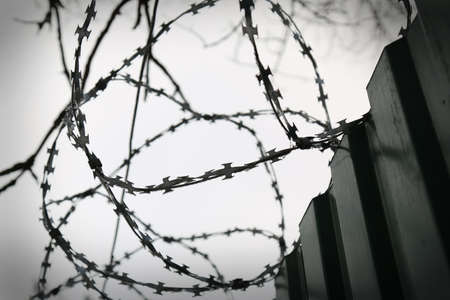 Fence with barbed wire close-up. Fence. Closed area. Prison. Protected area. Background.の写真素材