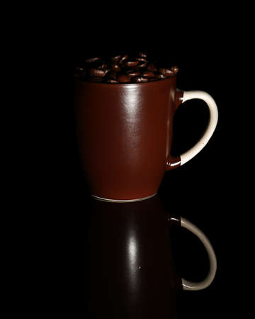 Roasted coffee beans lie in dark brown mugs, on a black background. isolated. close-up.の写真素材