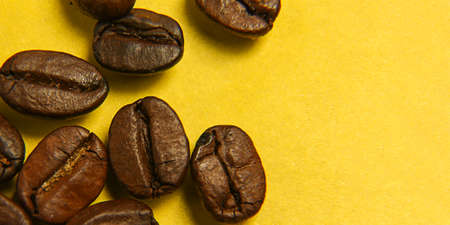 Roasted coffee beans on a yellow background. Macro photography. Close-up. Coffee seeds. Arabica.の写真素材