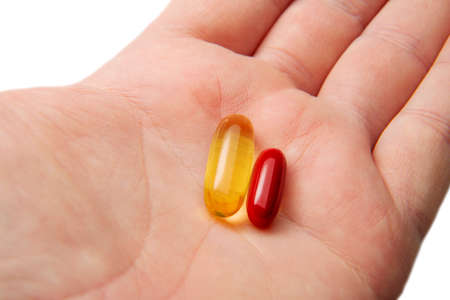 Two medicines capsules tablets are in the man's hand. The concept of decision making medicine.の写真素材