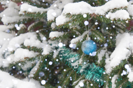 The background is without sharpness, there is no focus. Winter, festive, Christmas background. A Christmas tree decorated with toys and tinsel. Snowfall. Falling snow. Bokeh.の写真素材