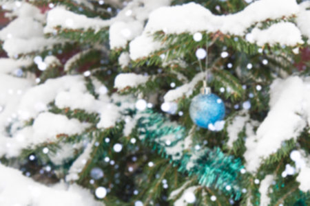The background is without sharpness, there is no focus. Winter, festive, Christmas background. A Christmas tree decorated with toys and tinsel. Snowfall. Falling snow. Bokeh.の写真素材