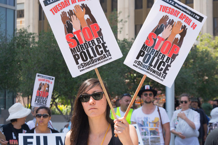 Los Angeles, CA, USA - April 14, 2015:  Woman holding two signs during Stop Murder by Police. Protest against the brutalization and murdering of black and latino people by police for decades without consequence.のeditorial素材