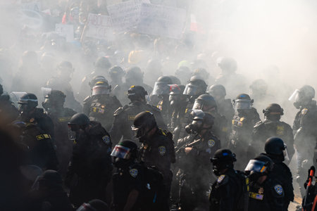 Los Angeles, USA â€“ June 8, 2025: Los Angeles riot police confronting protesters, engulfed in...