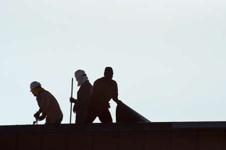 Silhouettes of three men at work の写真素材