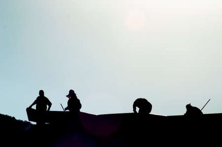 Silhouettes of four workers on a rooftop.の写真素材