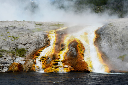 Firehole Geyser erupting into the river in Yellowstoneの写真素材
