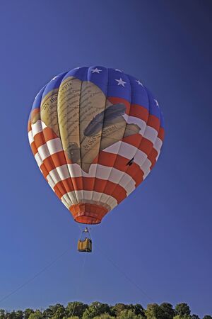 A colorful hot air balloon floats against a blue sky.の写真素材