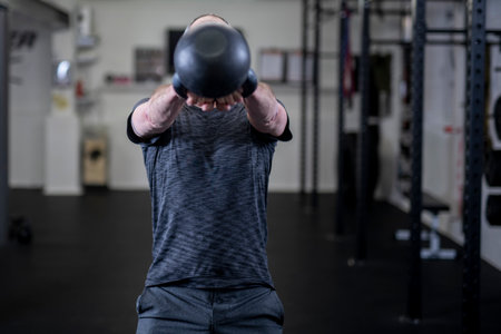 Portrait Of A Young Man Working Out With Kettle Bell In Gym