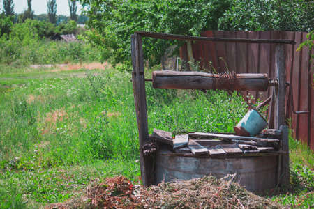rustic well in the countryside with trees and grassの写真素材