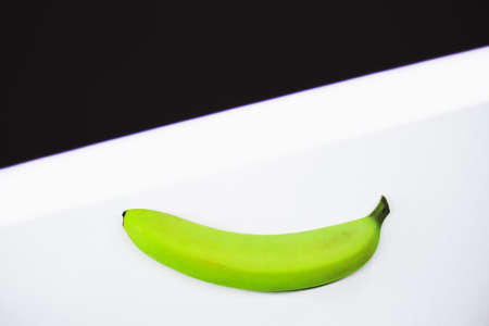 Single green banana against white background copy spaceの写真素材