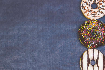 Multi-colored donuts close-up on a dark blue background copy spaceの写真素材