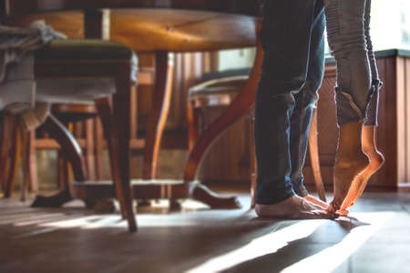 happy barefoot couple at the kitchen, girl standing on tiptoe try to kiss husbandの写真素材